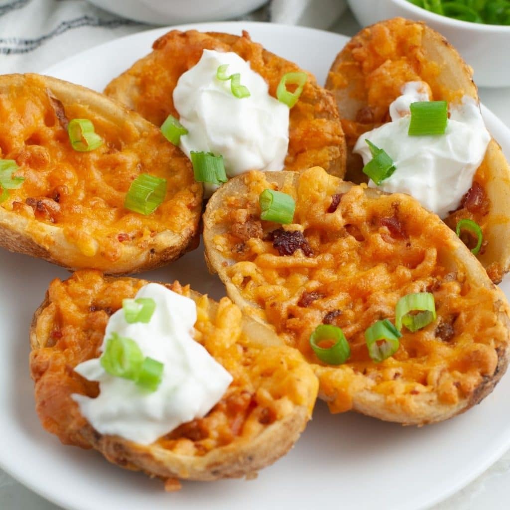Plate of cooked potato skins topped with sour cream. 