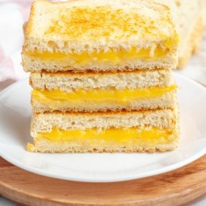 Stacked grilled cheese sandwiches on a plate.