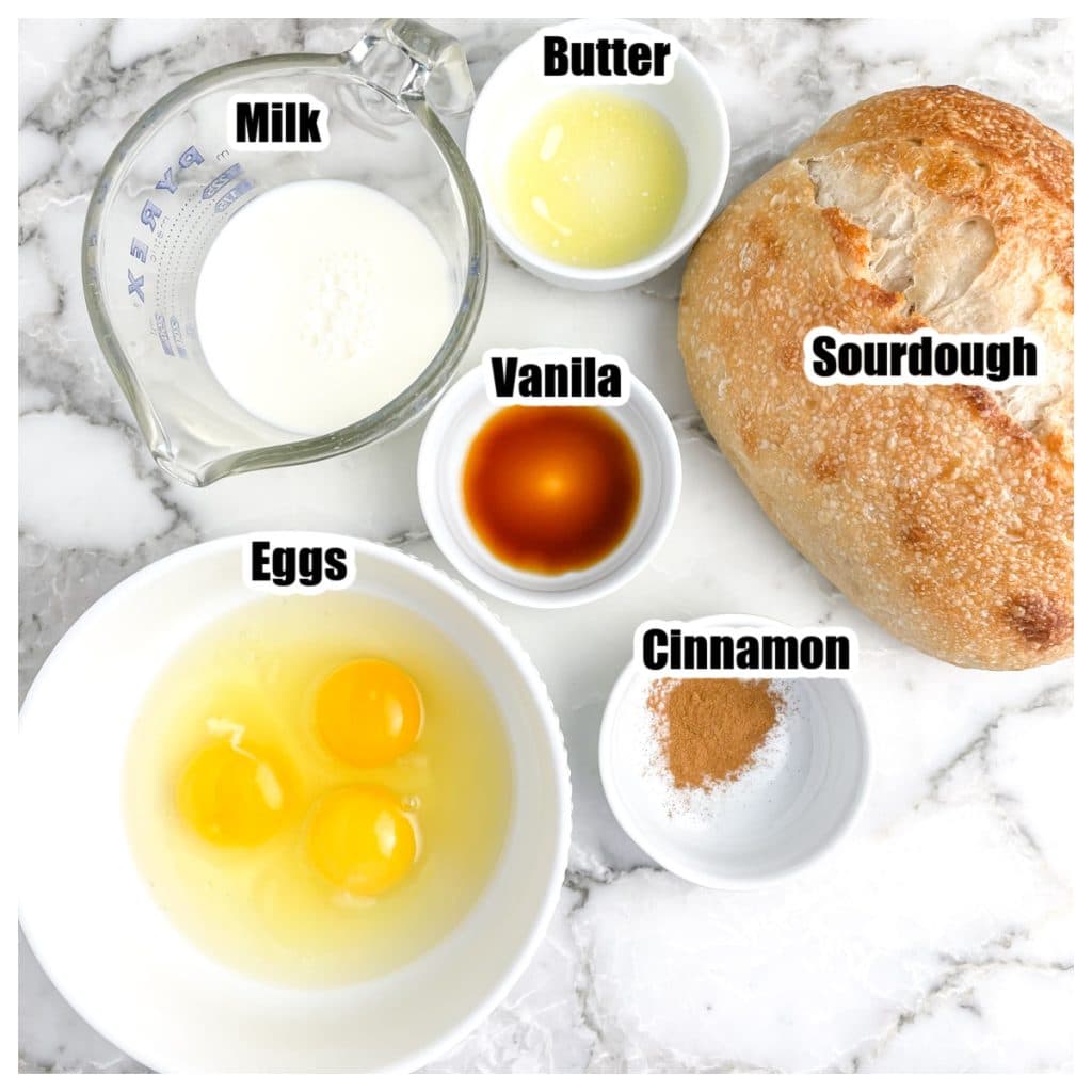 Bowl of eggs, milk, cinnamon, butter, vanilla, and loaf of sourdough.
