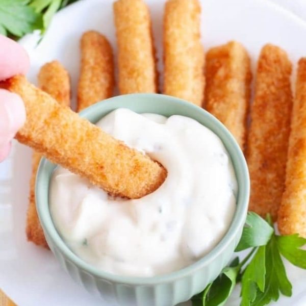 Bowl of tartar sauce and fish sticks.