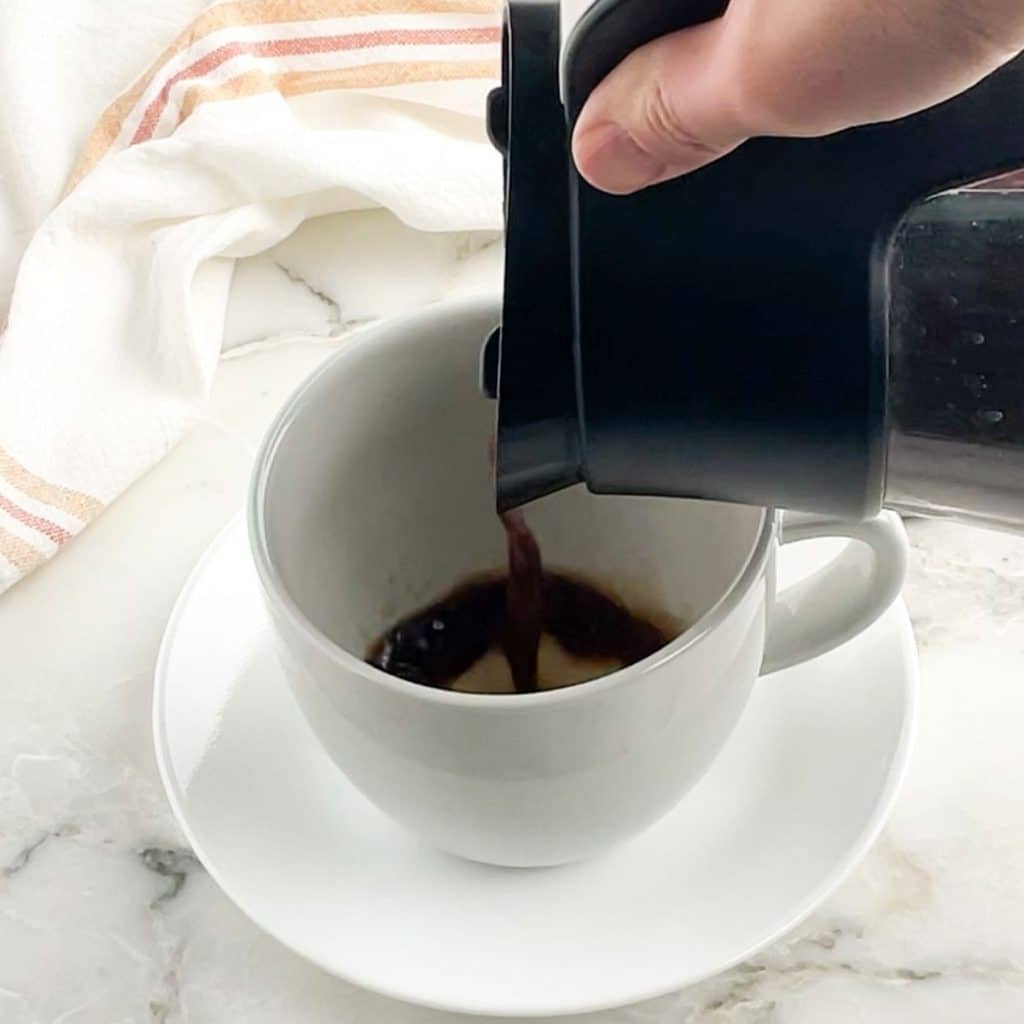 Coffee pouring into white mug.