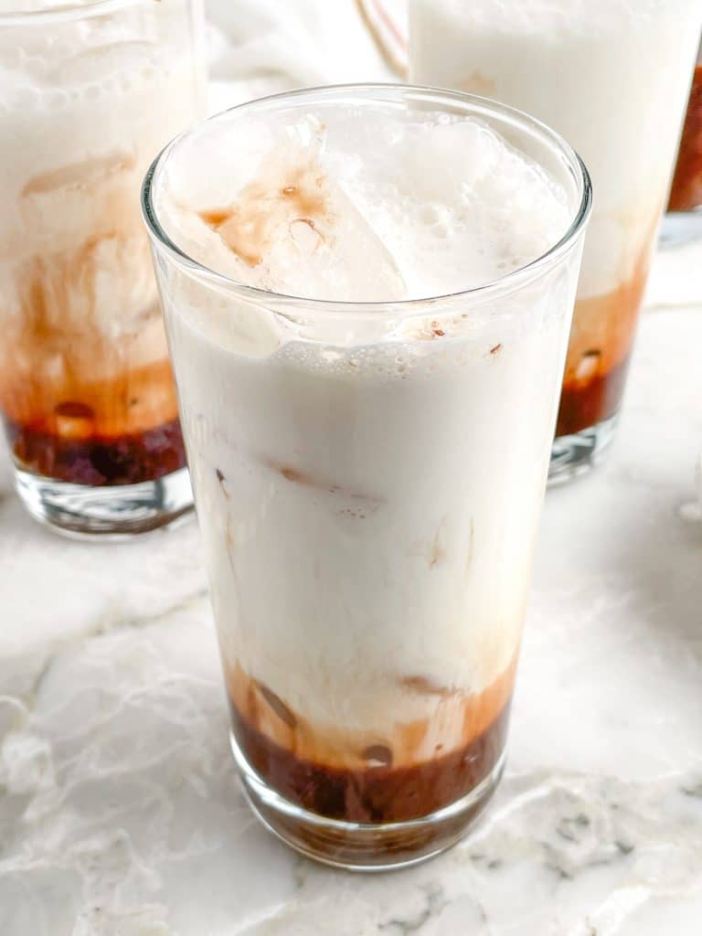 Tall glass with ice and cream.