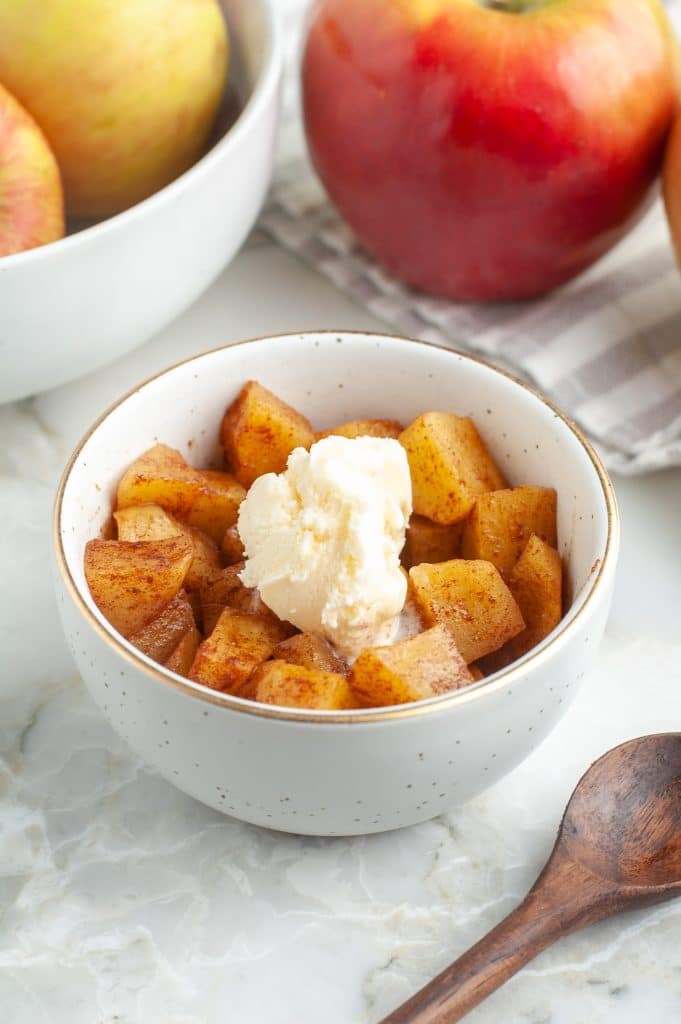 Bowl with cinnamon apples topped with scoop of ice cream.
