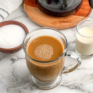 Cup of coffee with bowl of sugar and cream.