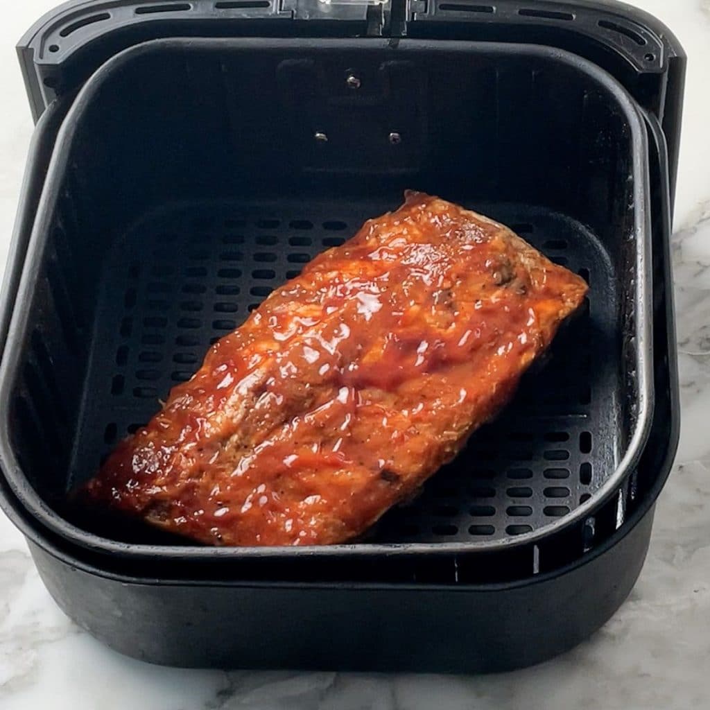 Cooked ribs in an air fryer basket.