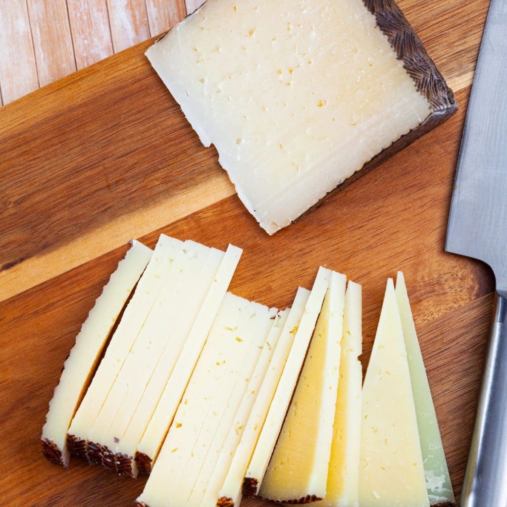 Slices of Anejo cheese on cutting board.