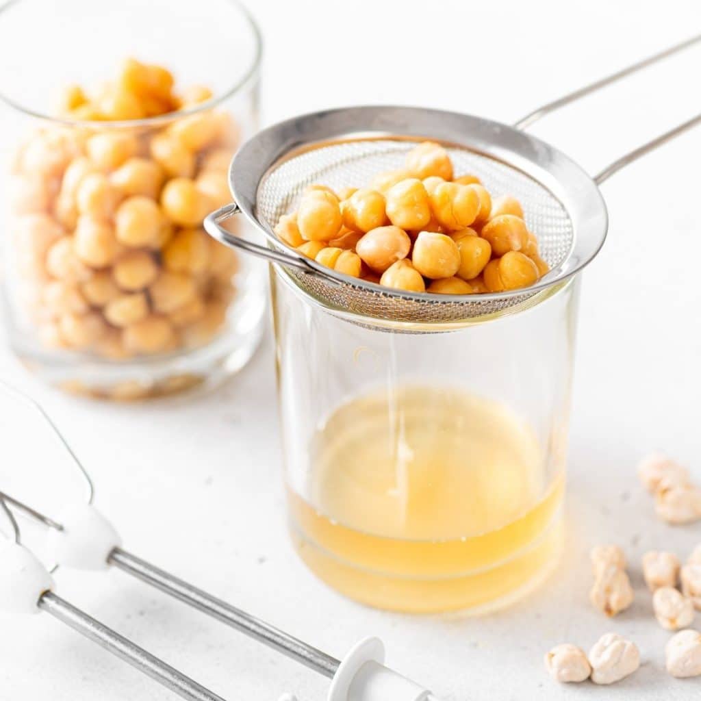 Strainer with chickpeas and liquid in a cup. 