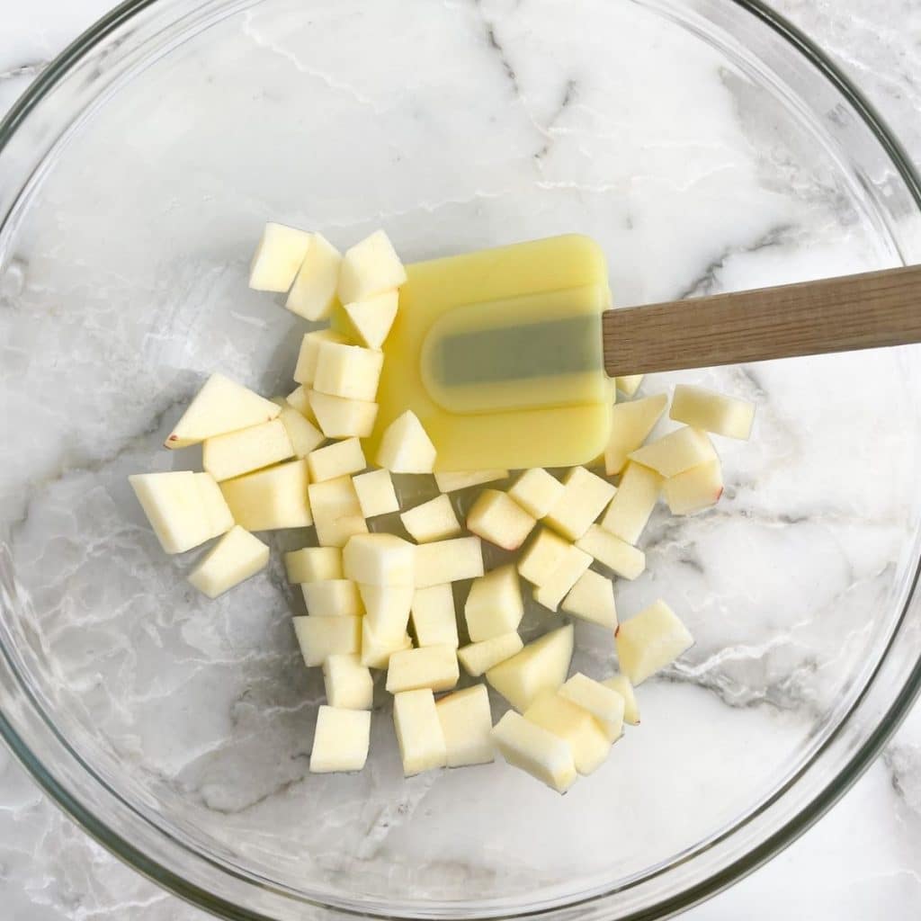 Diced apples in a bowl with a spatula.