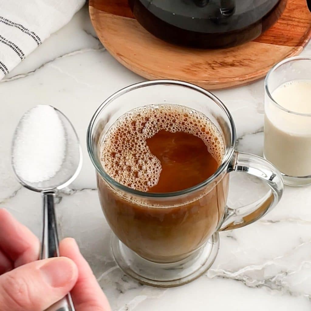 Mug of coffee with spoon of sugar.