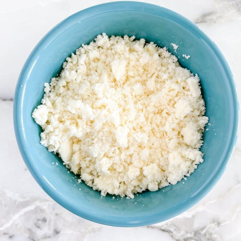 Blue bowl of crumbled white cheese.