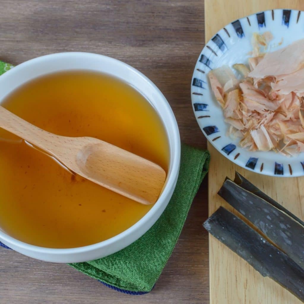 Bowl of broth with a wooden spoon.