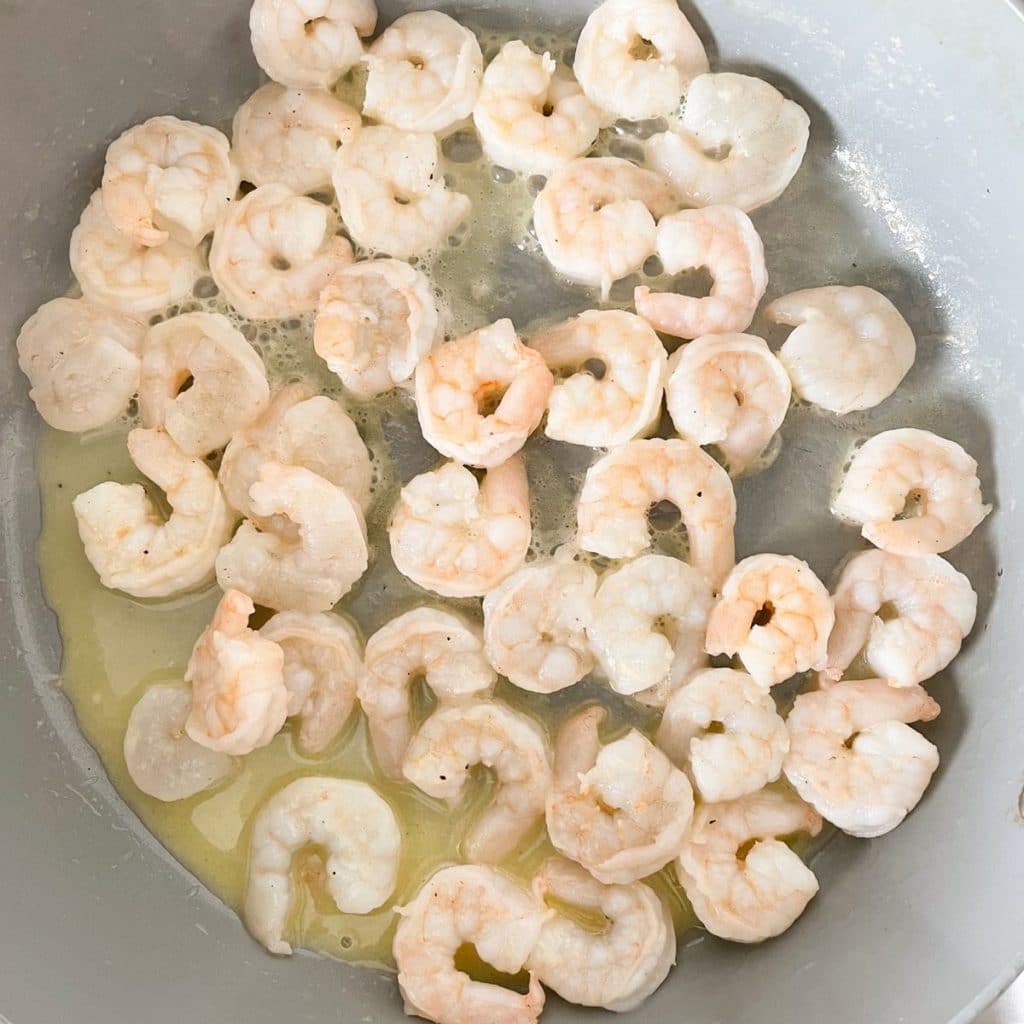 Skillet with cooked shrimp and melted butter. 