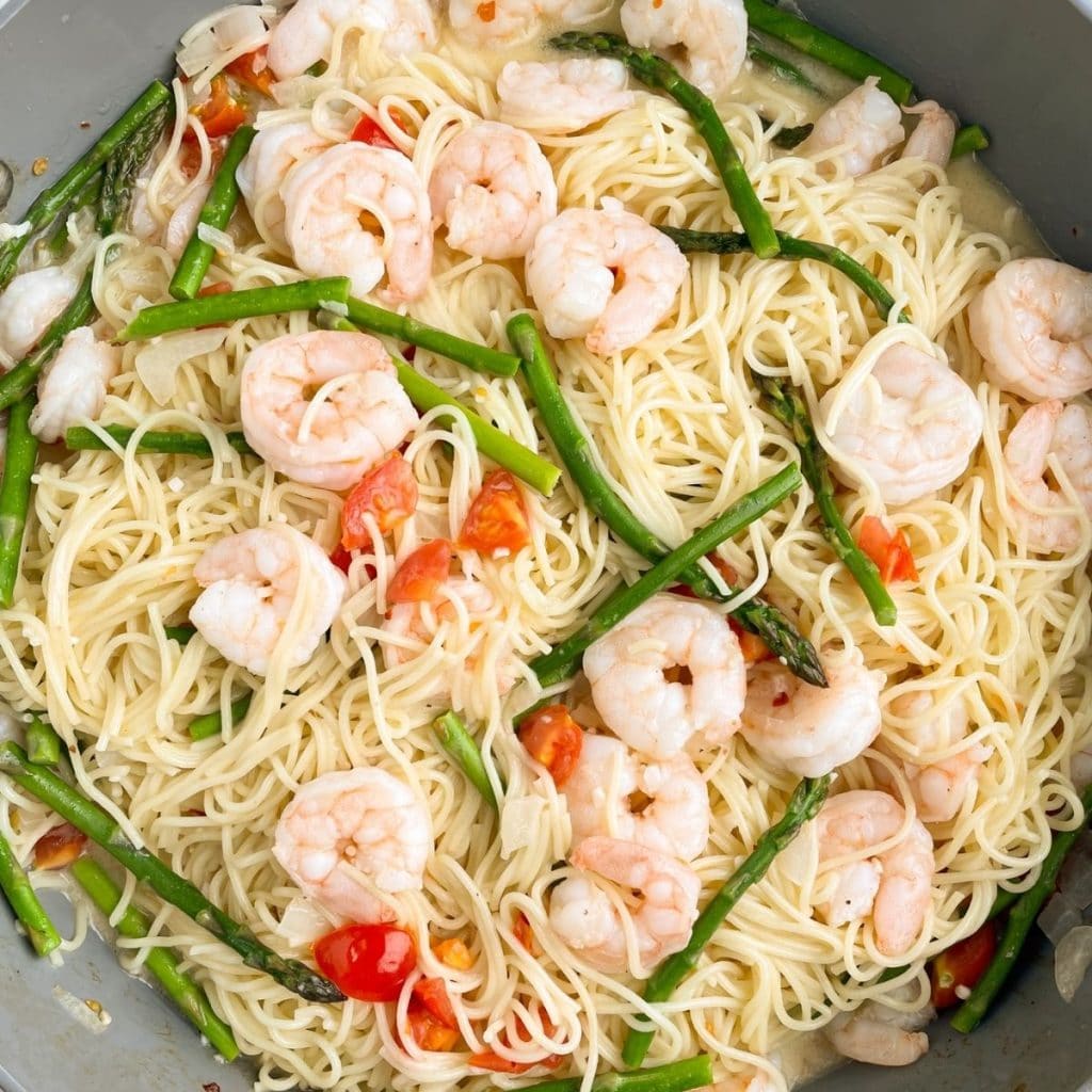 Skillet with pasta, shrimp, asparagus, and diced tomatoes.