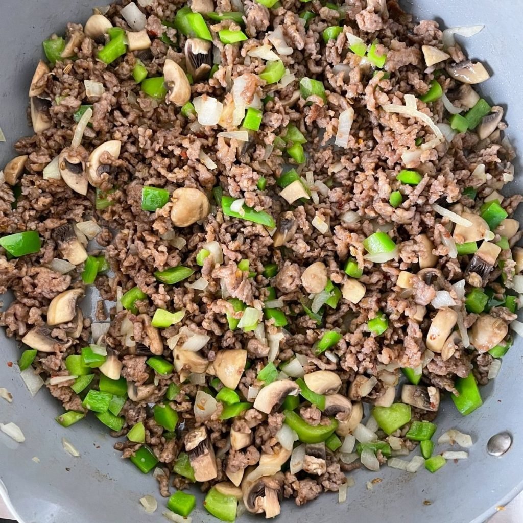 Skillet of ground sausage, green bell pepper, onion, and mushrooms.