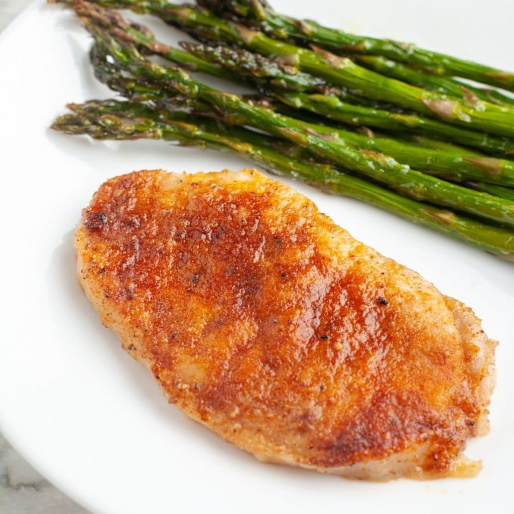 Pork chop on a plate with asparagus. 