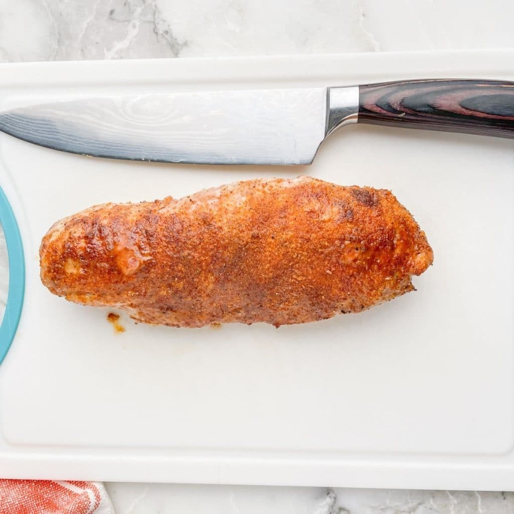 Cooked pork tenderloin on a cutting board.