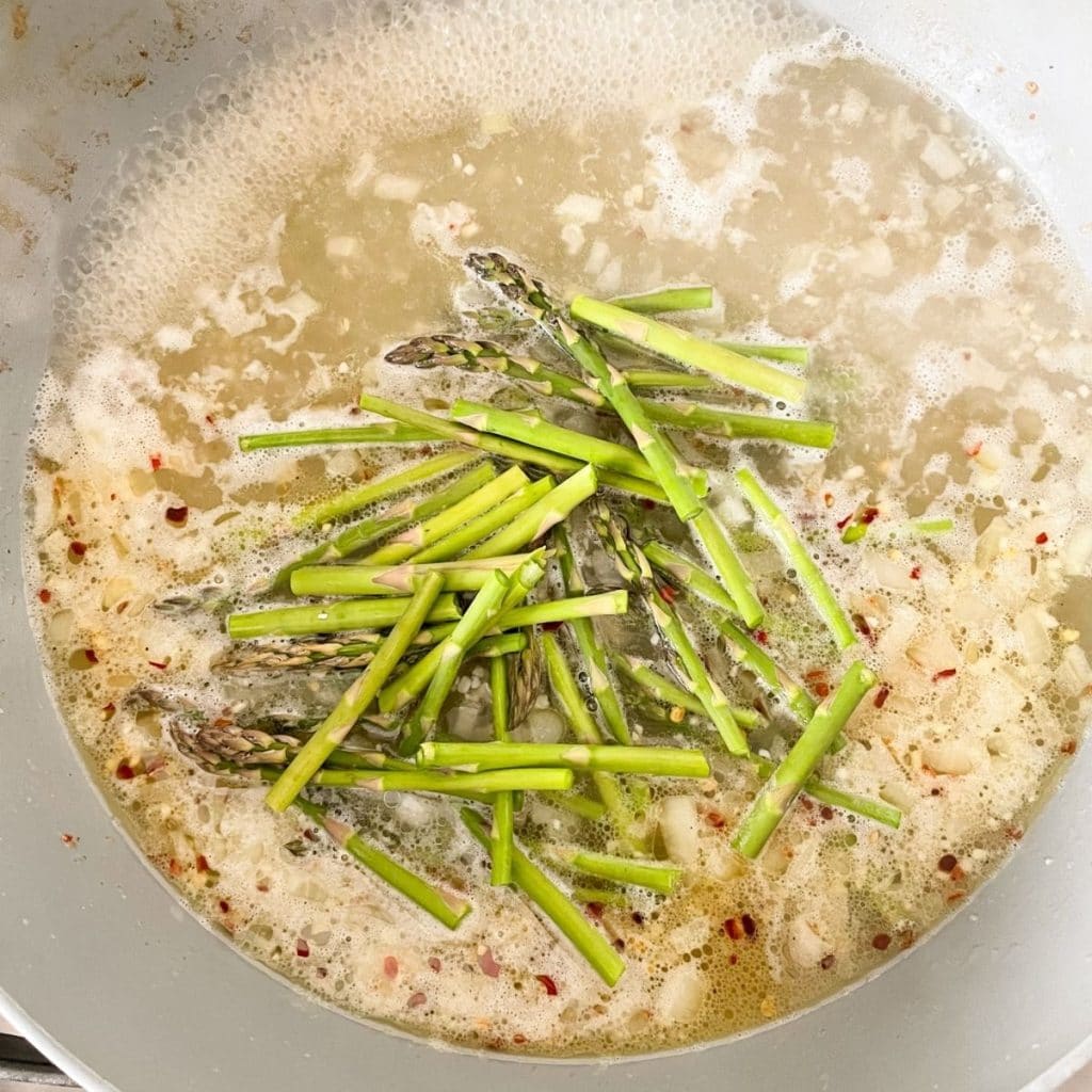 Skillet with butter, onion, asparagus, and garlic.