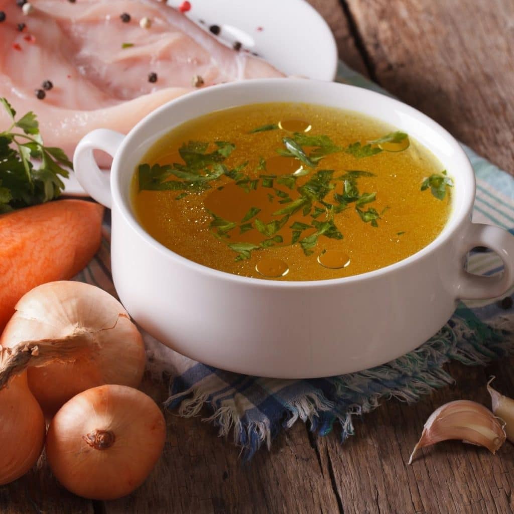 Bowl of chicken broth, carrots, and chicken.