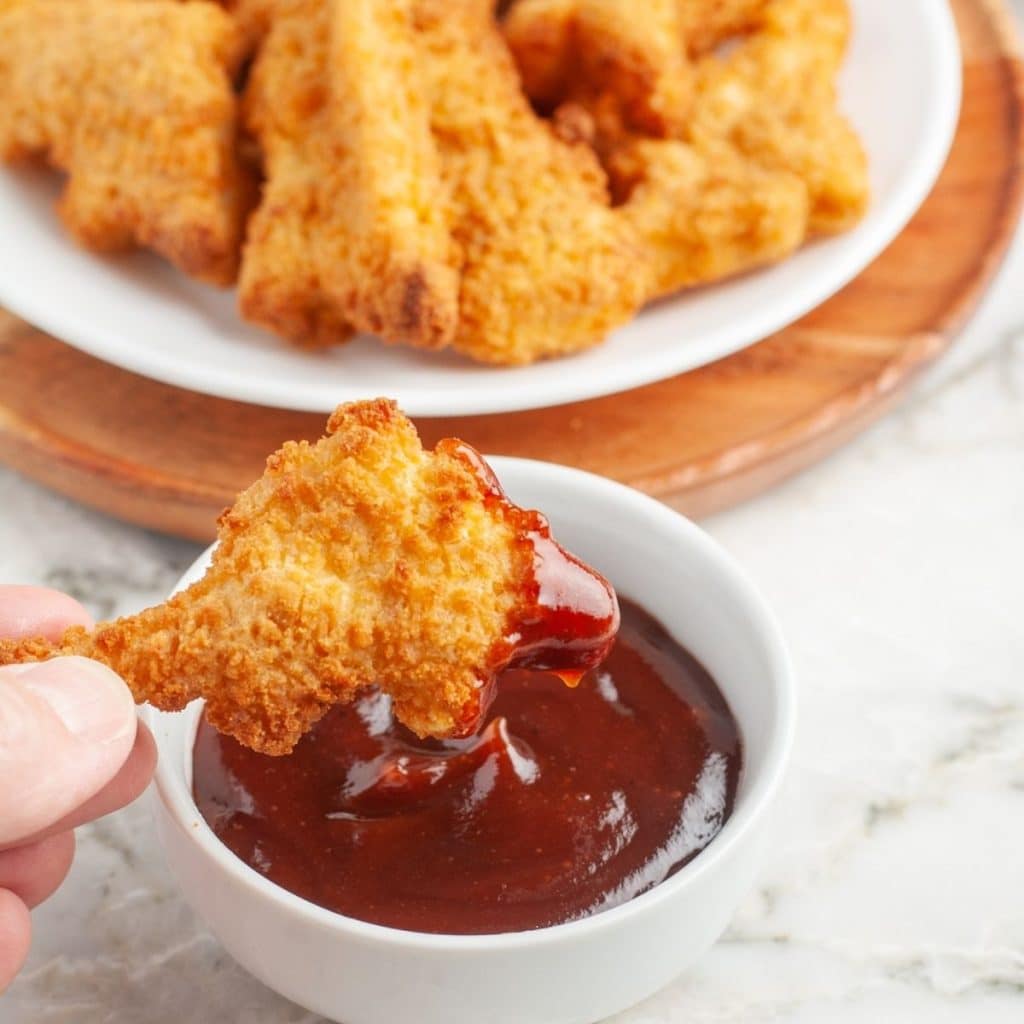 Dino chicken nugget dipped in BBQ sauce.