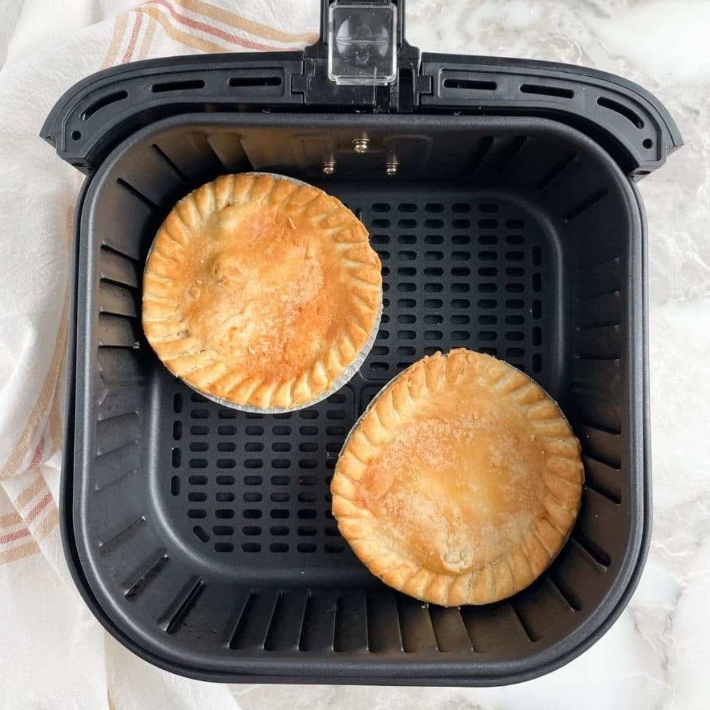 Two mini pot pies in air fryer basket.