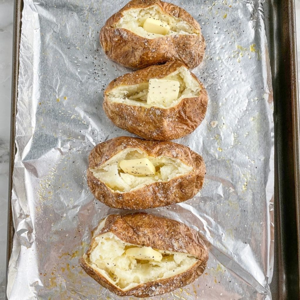 Cooked baked potatoes on a baking pan. 