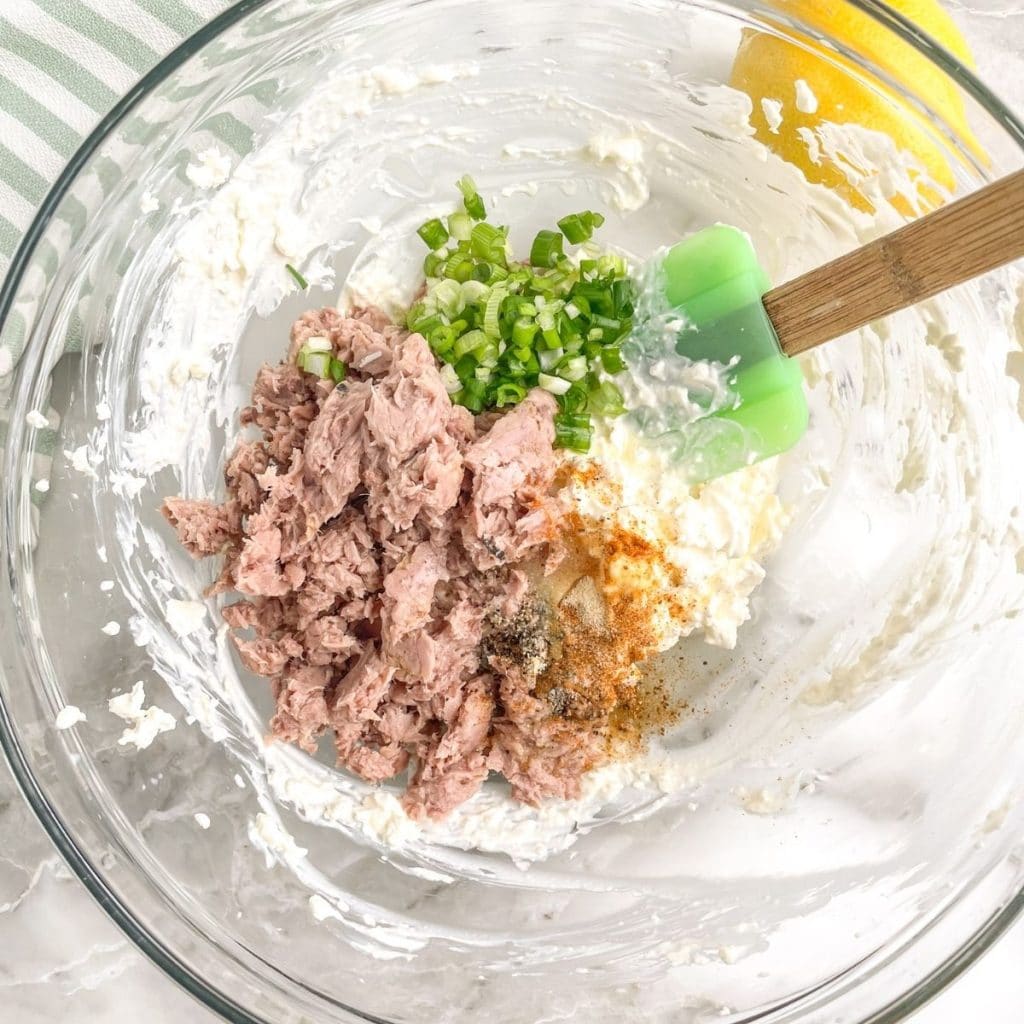 Large bowl with canned tuna, mayonnaise, green onion and a spatula.