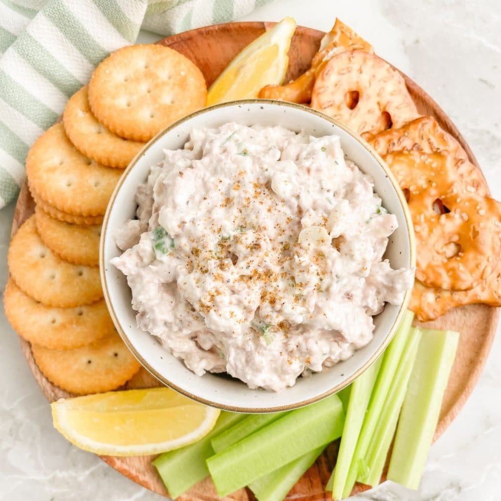 Bowl of tuna dip with crackers and celery sticks.