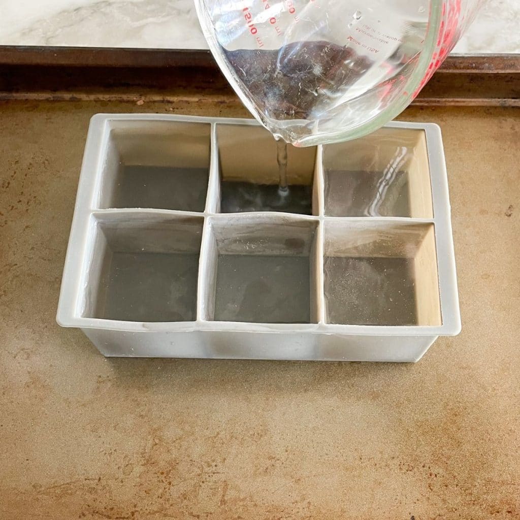 Water pouring into ice cube tray.