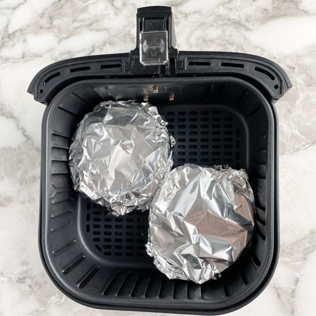 Foil covered mini pot pies in an air fryer basket. 