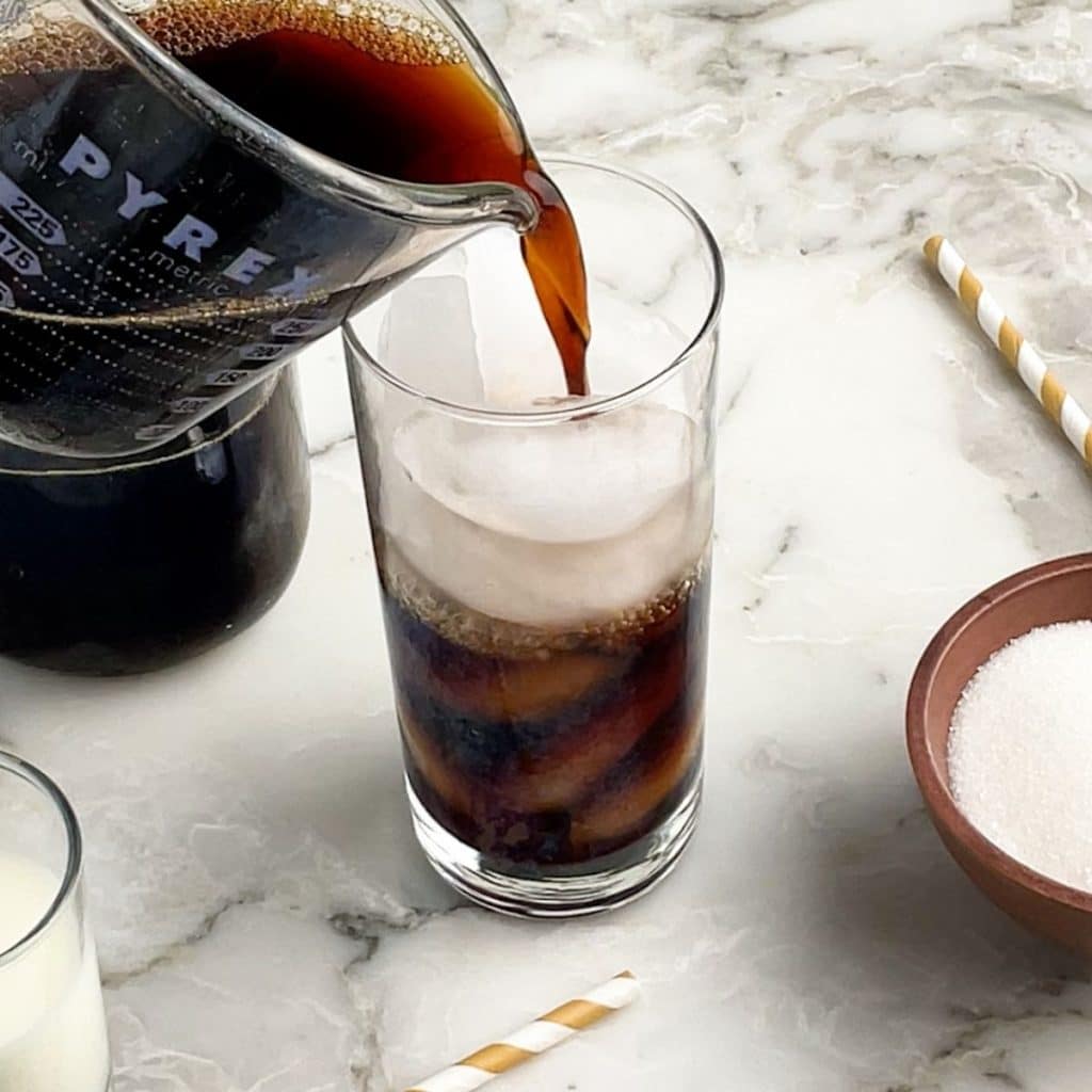 Coffee pouring into glass with ice.