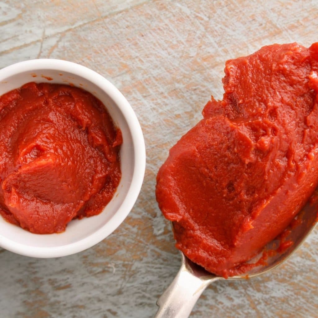 Bowl and spoon of tomato puree.