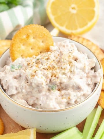 Bowl of dip with Ritz cracker in it.