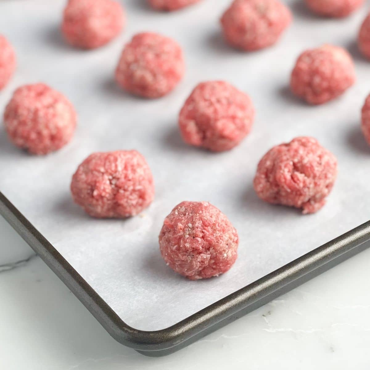 The Perfect Timing for Baked Meatballs 4 A baking pan neatly arranged with uncooked meatballs, ready for baking.