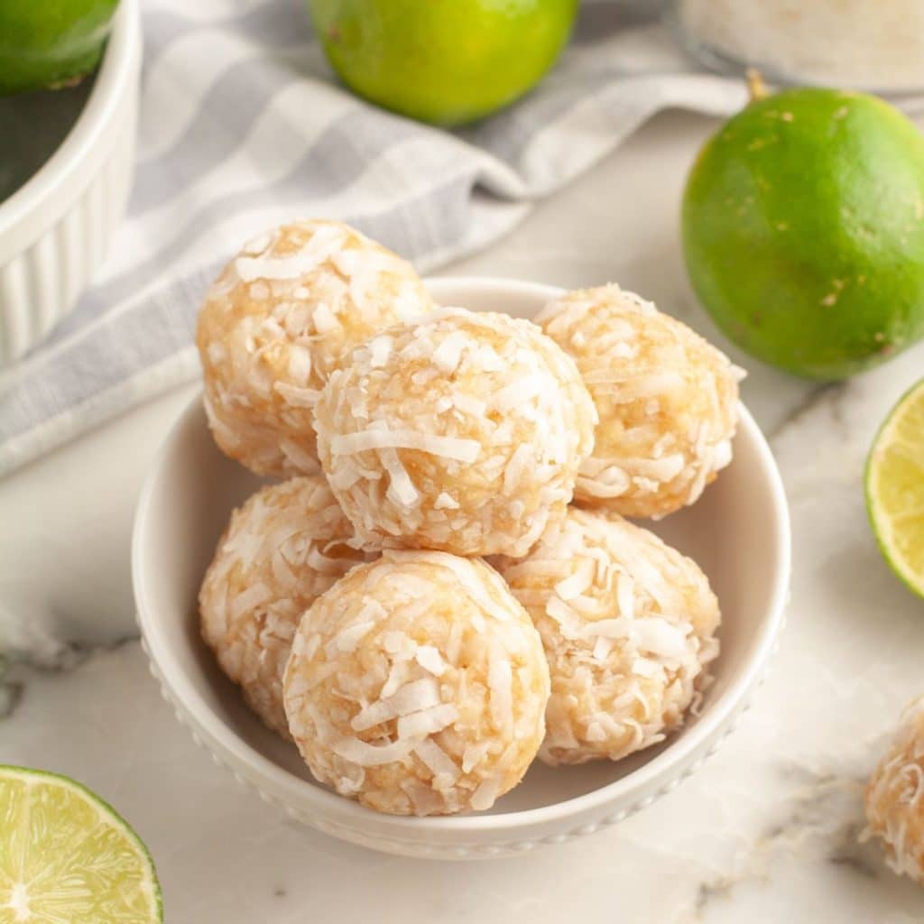 Bowl of coconut balls and limes on the side. 