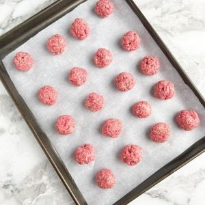 Uncooked meatballs on a baking sheet.