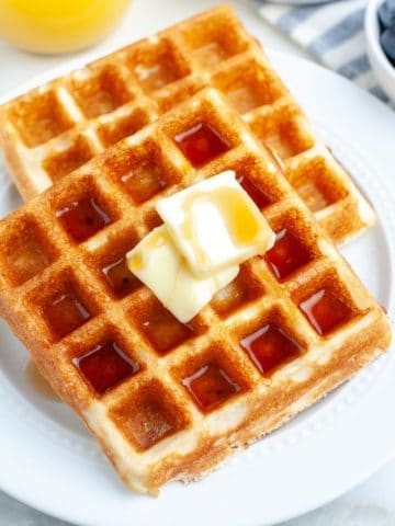 Two waffles with butter and syrup.