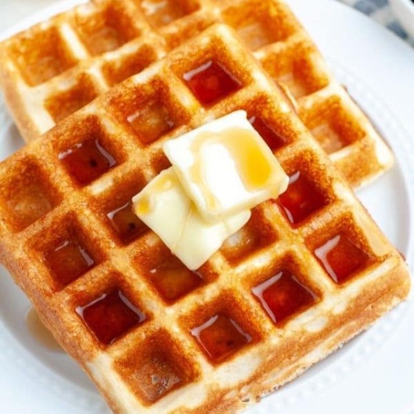 Two waffles with butter and syrup.