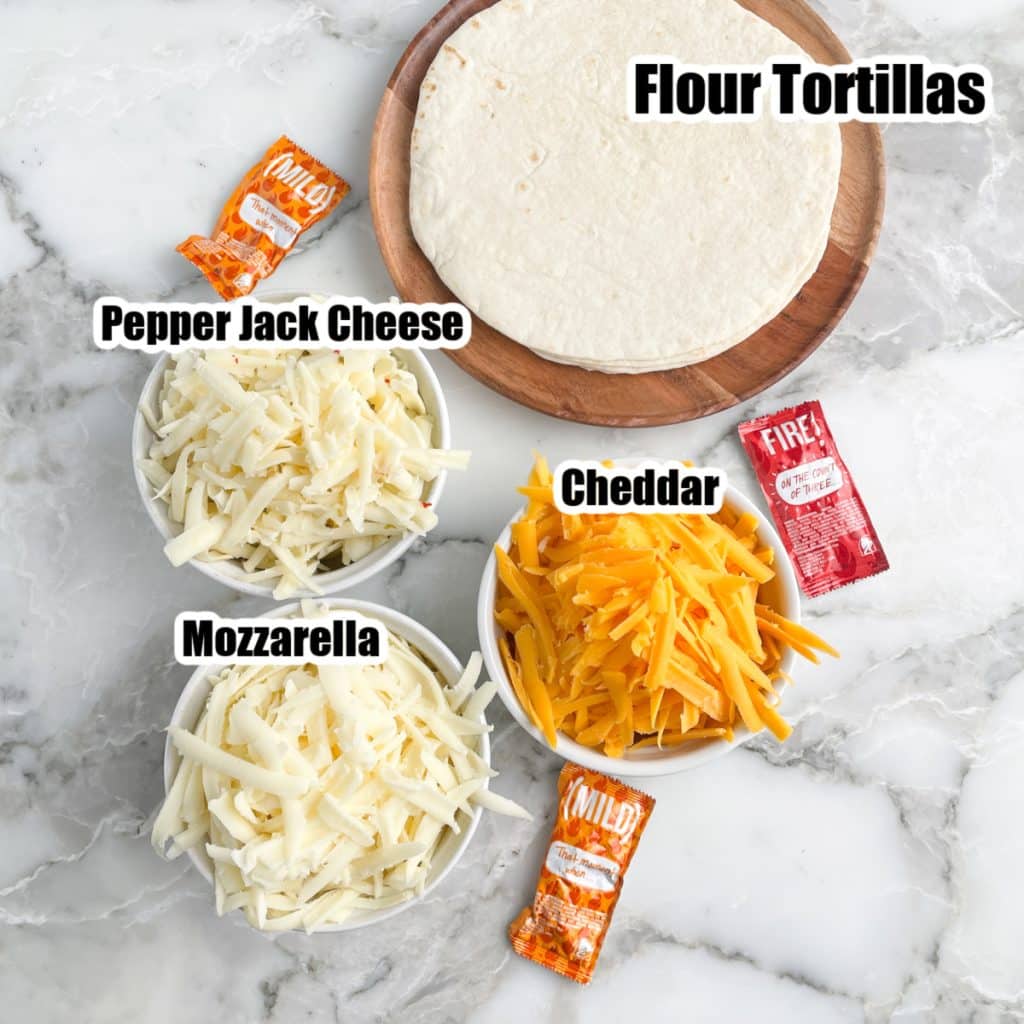 Three bowls of shredded cheese and tortillas. 
