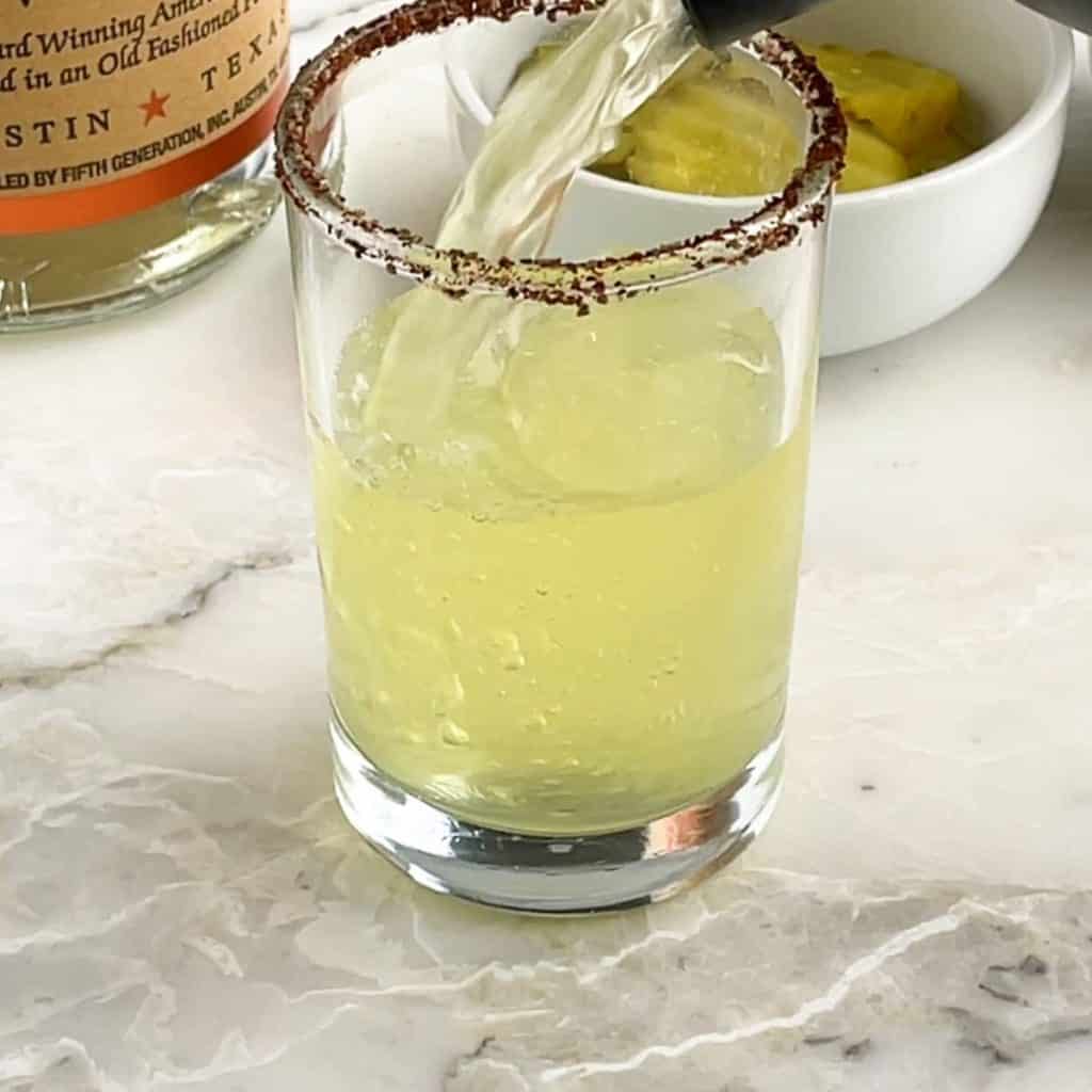 Green juice pouring into shot glass.