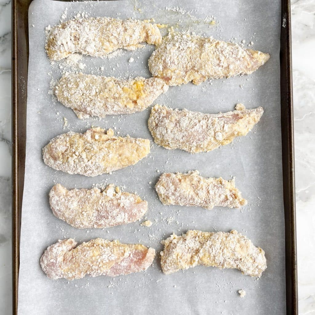 Sheet pan with breaded chicken tenders. 