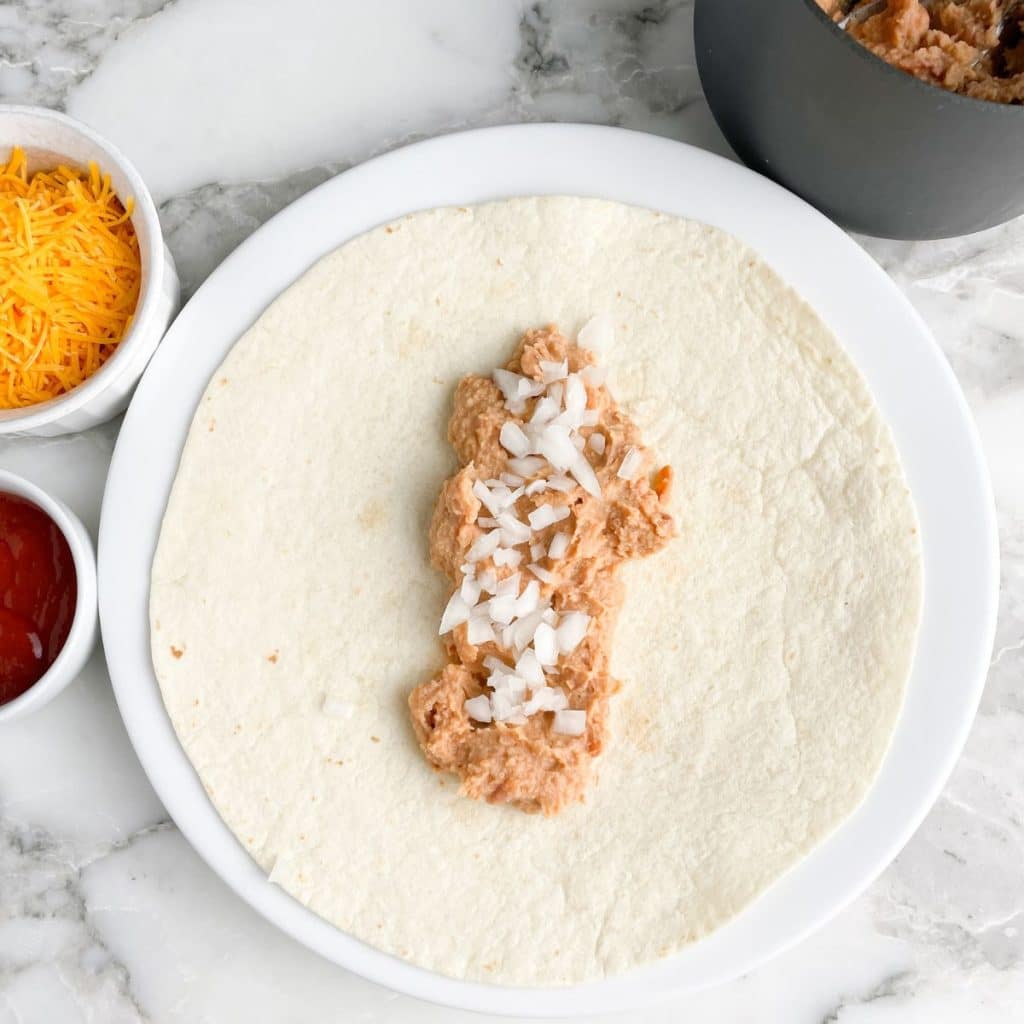 Tortilla topped with refried beans and onion.