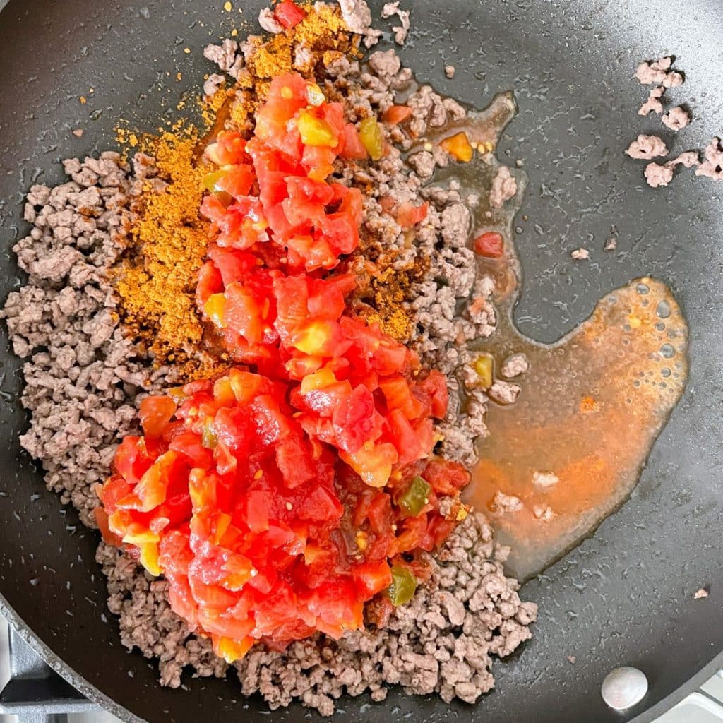 Skillet with ground beef and diced tomatoes. 