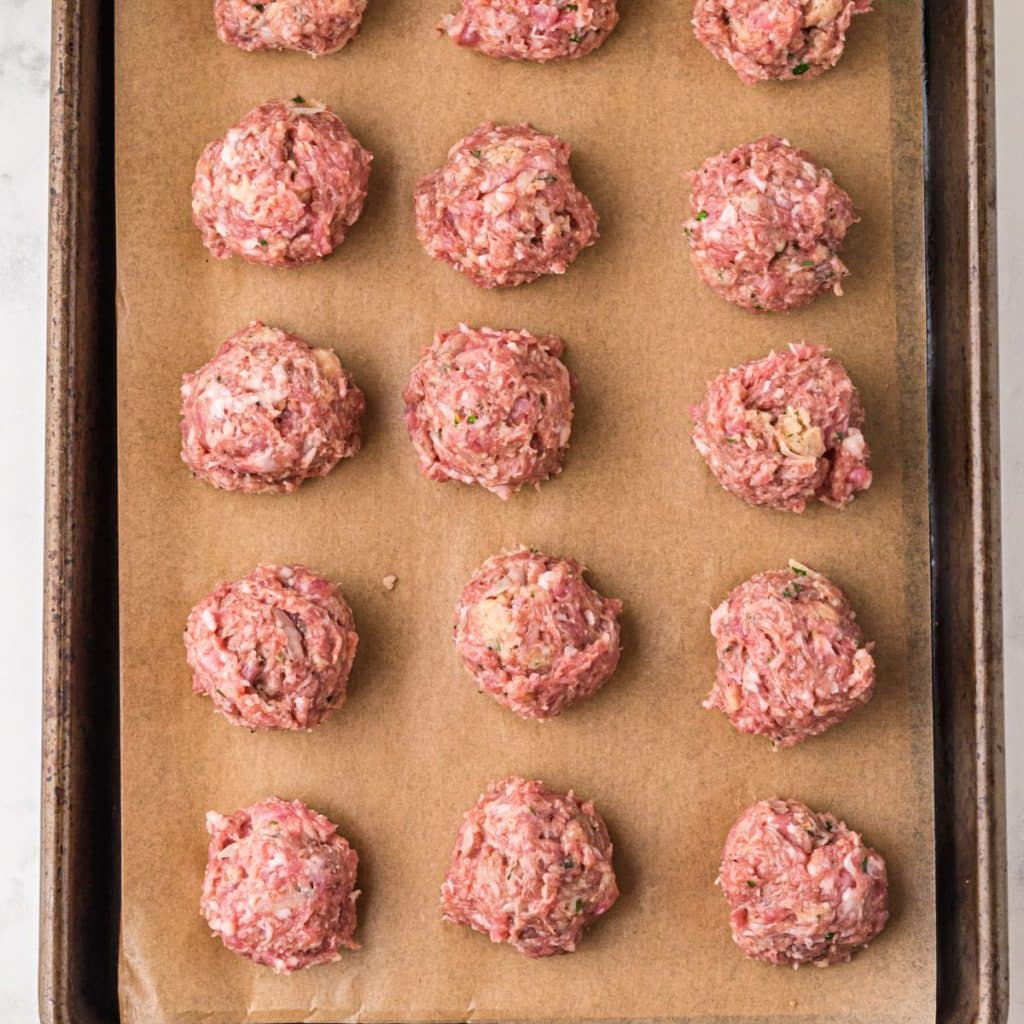 Uncooked meatballs on a baking sheet.