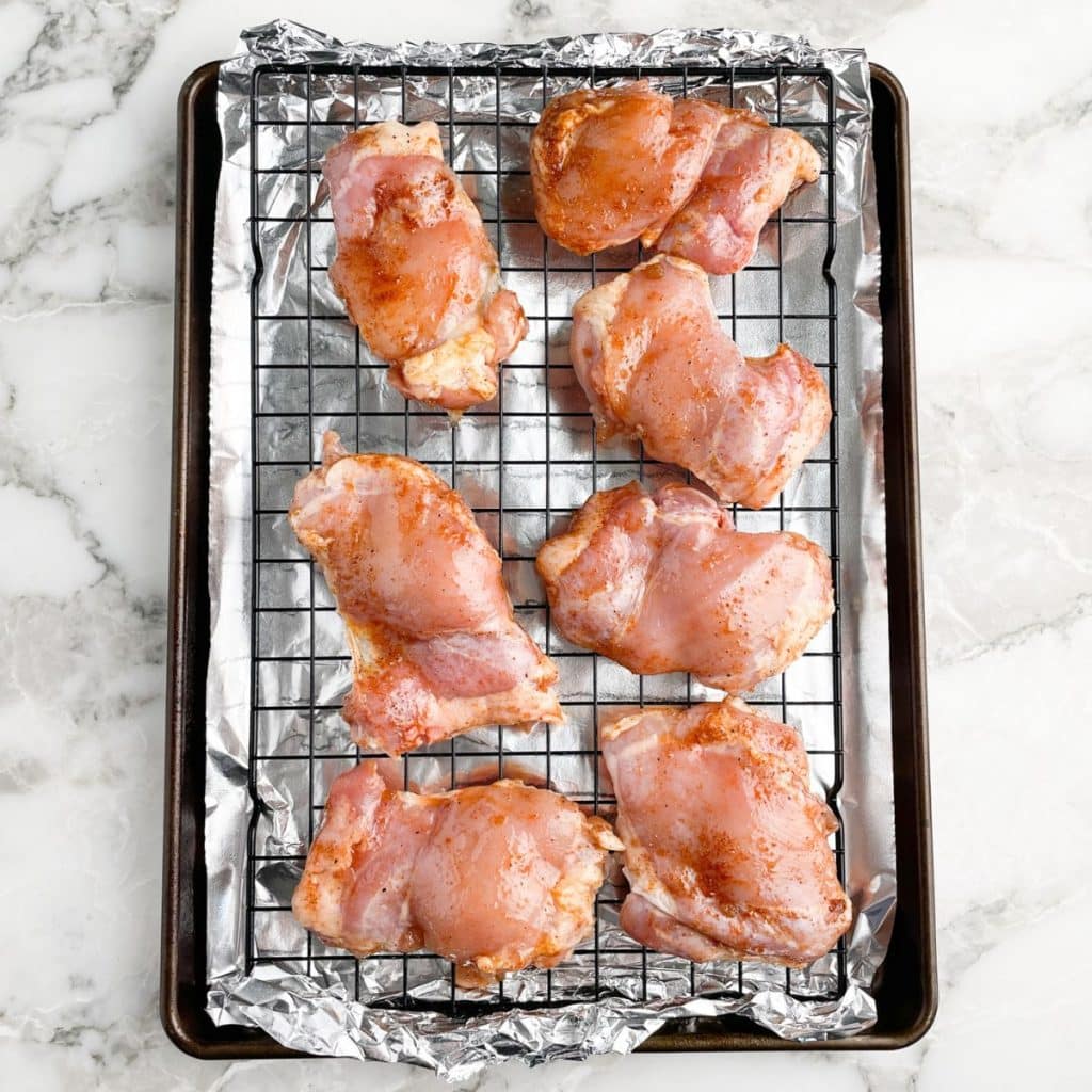 Uncooked chicken thighs on baking sheet. 