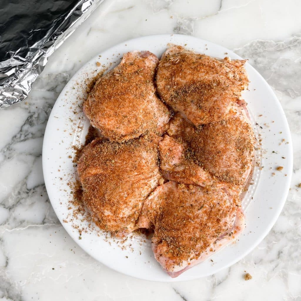 Plate of uncooked chicken thighs.