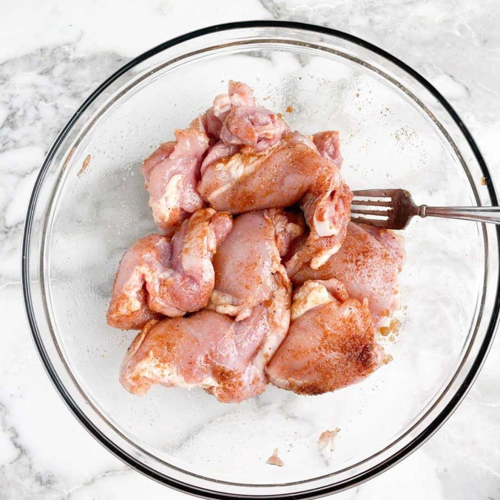 Bowl with seasoned chicken thighs. 