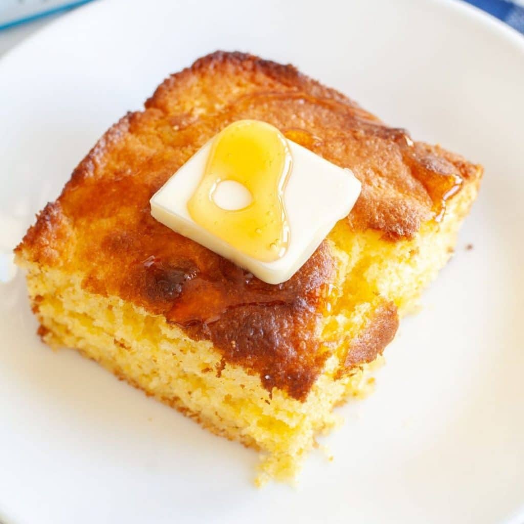 Piece of cornbread topped with pat of butter.