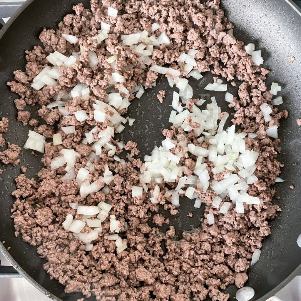 Skillet with ground beef and diced onion. 
