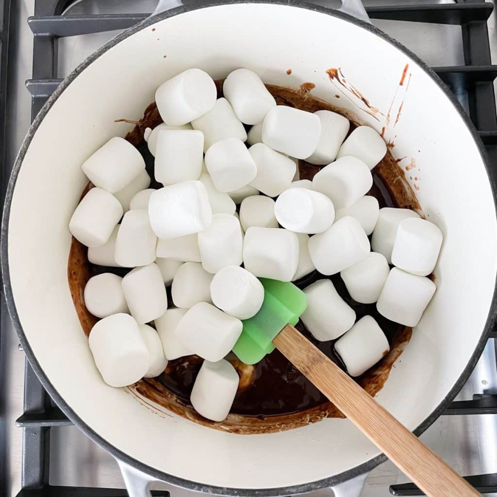 Saucepan with large marshmallows, melted chocolate, and spatula. 