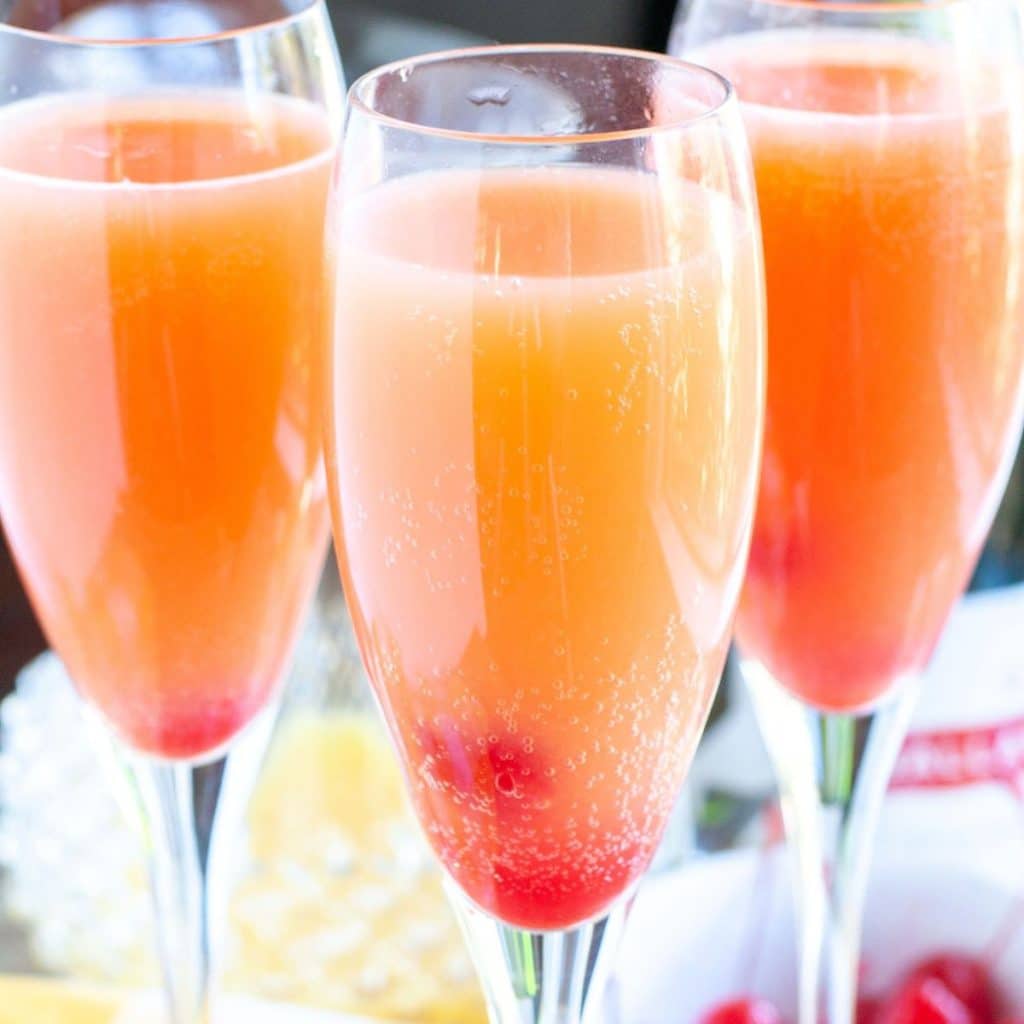 Three glasses of pink mimosas.
